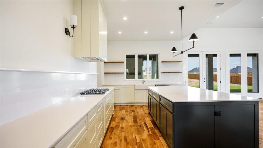 Kitchen featuring light wood-type flooring, a healthy amount of sunlight, a kitchen island, and decorative light fixtures