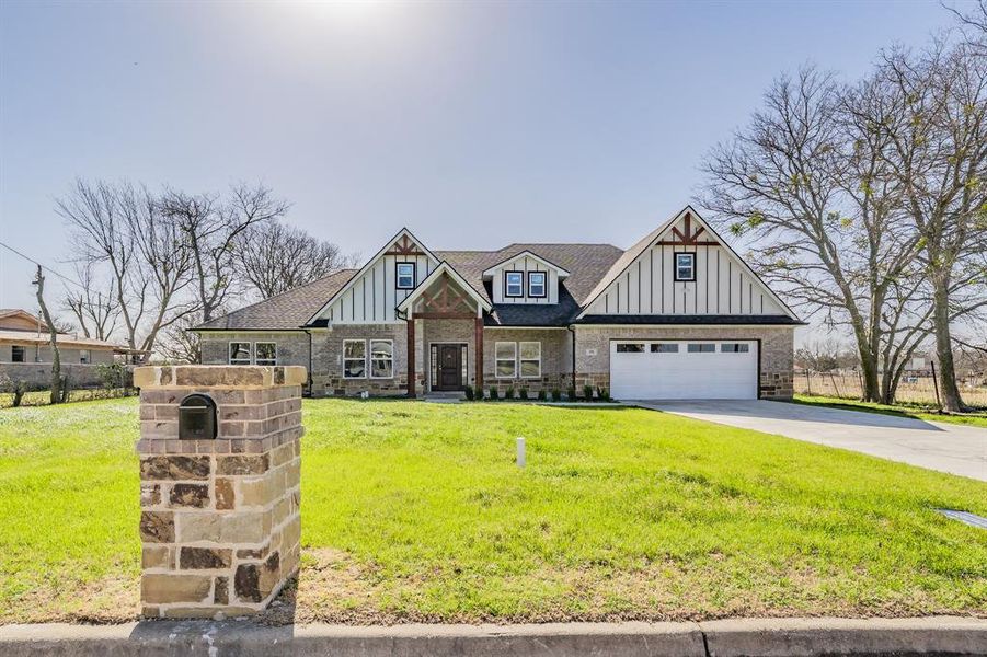 View of front facade with concrete driveway, brick siding, board and batten siding, and a front yard