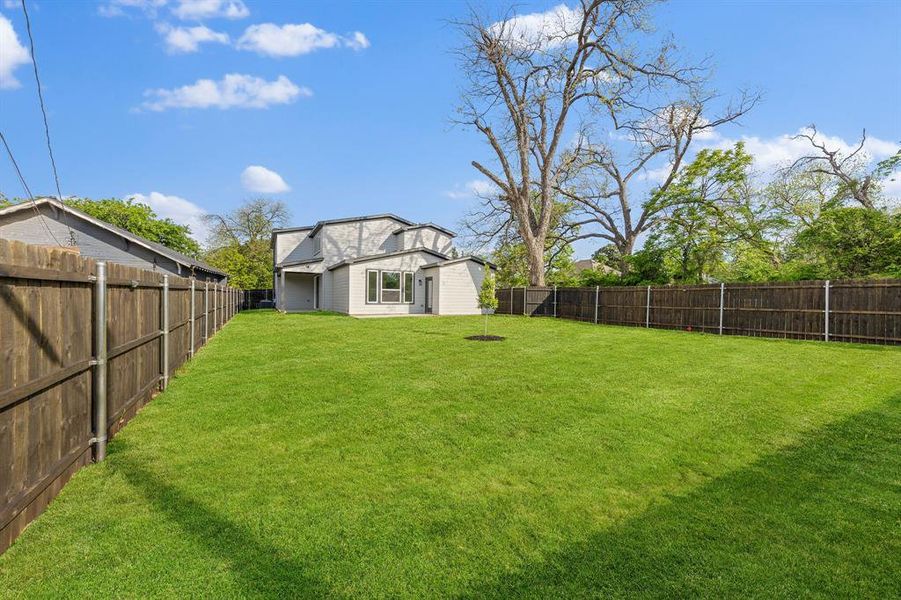 Extensive backyard with a manicured lawn, a wooden privacy fence, and mature trees visible beyond the fence line Extensive backyard with a manicured lawn, a wooden privacy fence, and mature trees visible beyond the fence line