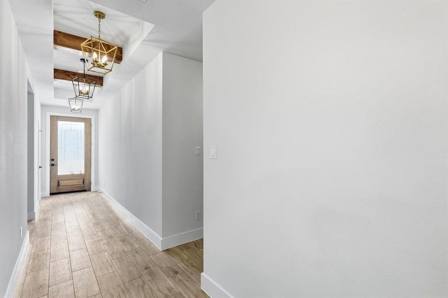 Corridor featuring wood finished floors, beamed ceiling, and a chandelier
