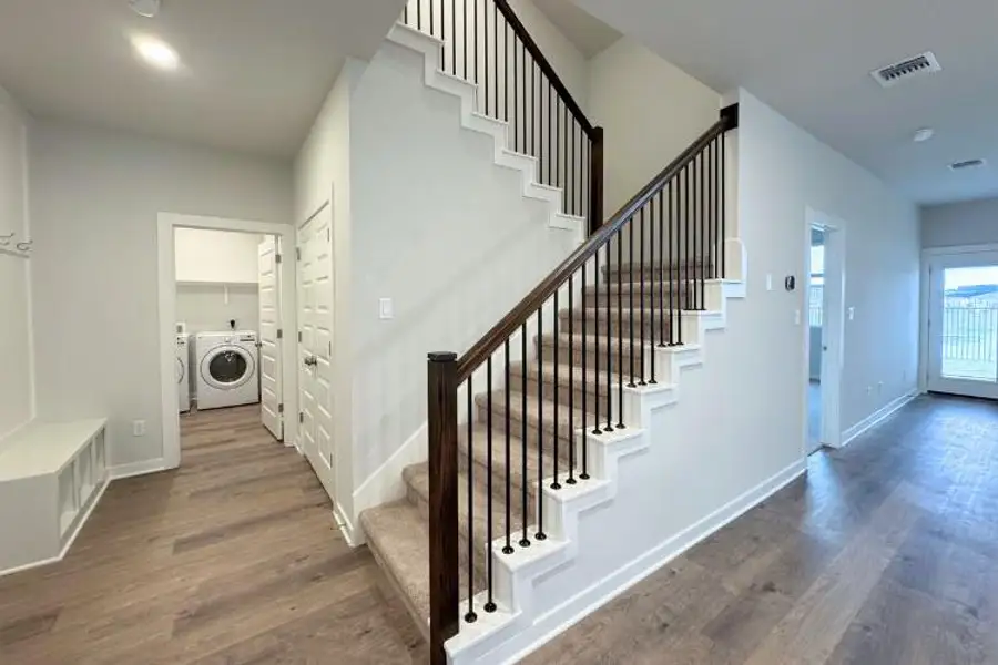 An elegant staircase features classic wood handrails and classic iron balusters near the entryway.