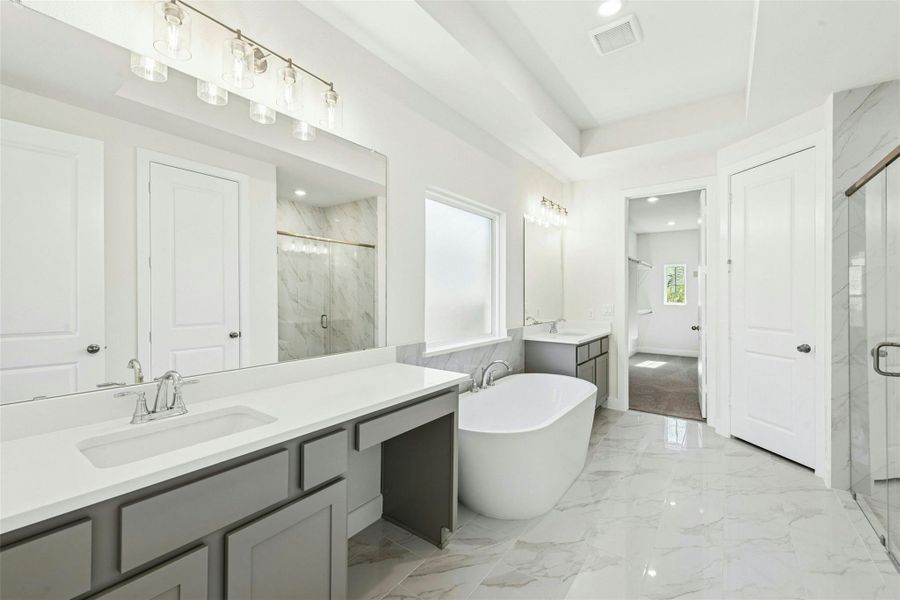 Bathroom featuring two vanities, a marble finish shower, light marble finish floors, a freestanding tub, and recessed lighting
