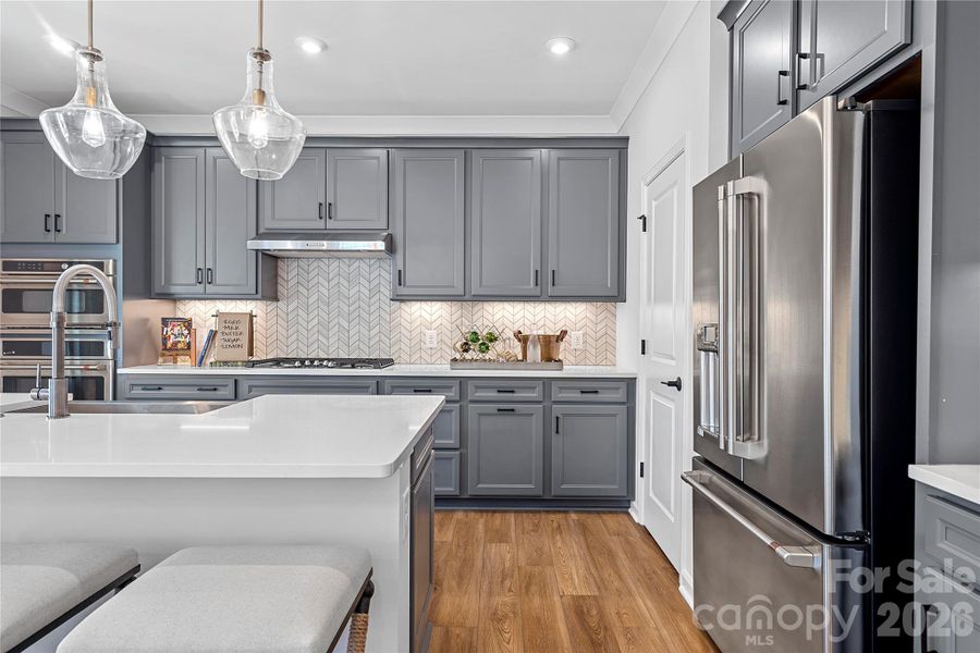 Rich grey cabinetry and quartz countertops paired with modern backsplash. Rich grey cabinetry and quartz countertops paired with modern backsplash.