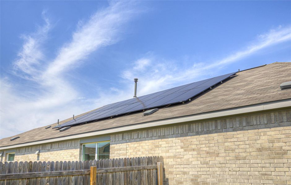 An energy-efficient residence features solar panels atop a durable shingle roof.
