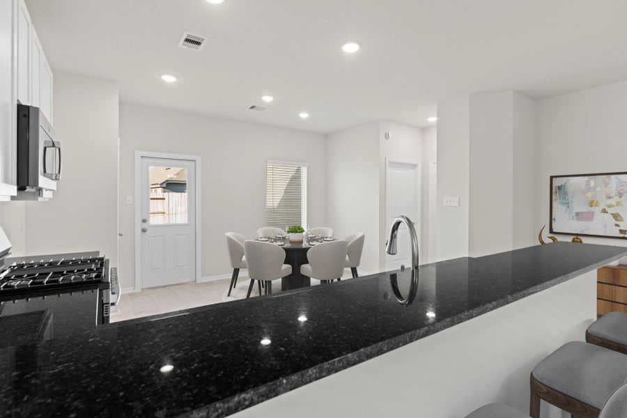The virtually staged kitchen view shows a perfect balance of elegance and practicality. Granite countertops, stainless-steel appliances, and a breakfast bar create a beautiful yet functional space for cooking and entertaining.