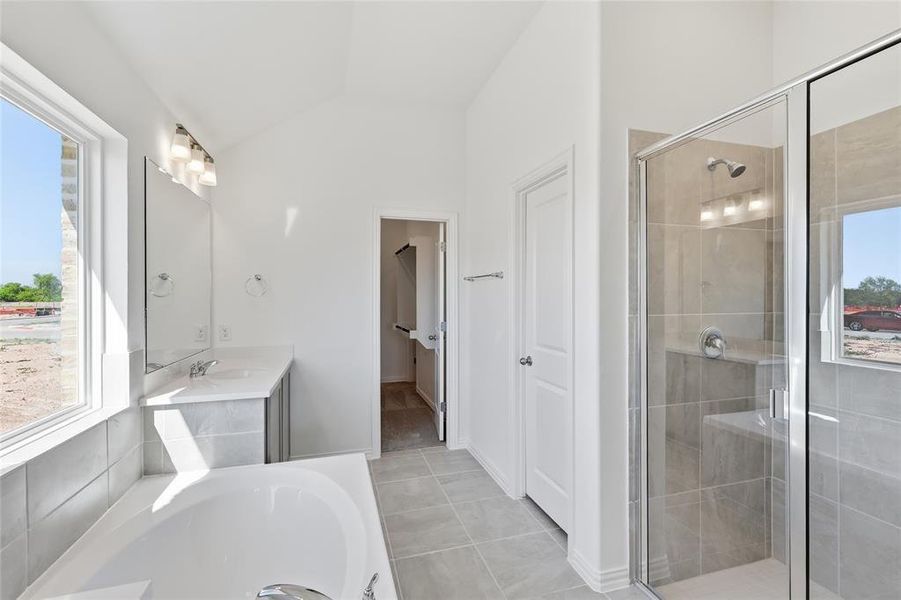 Bathroom featuring a built-in tub, dual vanity with undermount sinks, and a glass-enclosed shower with a built-in bench