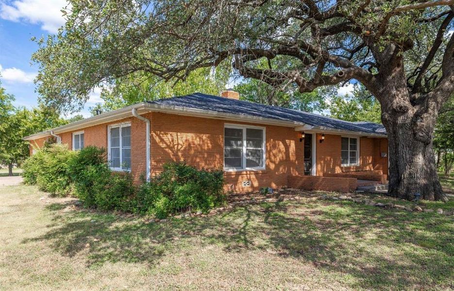View of home's exterior featuring brick siding, a chimney, and a lawn