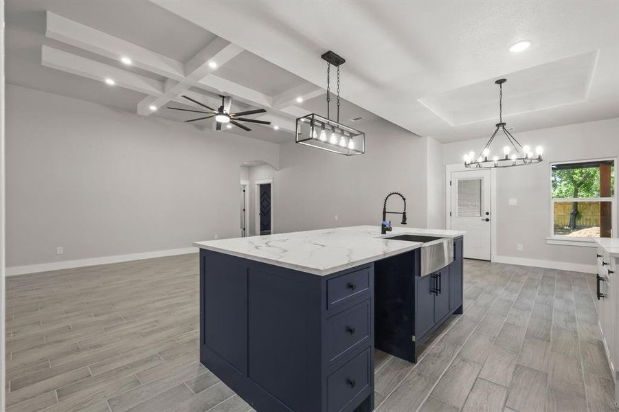 Kitchen featuring a sink, light wood-style flooring, open floor plan, baseboards, and a ceiling fan