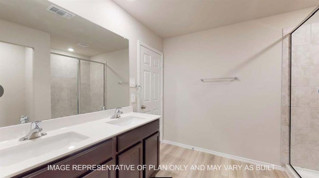 Bathroom featuring double vanity, a shower stall, and light wood-style floors