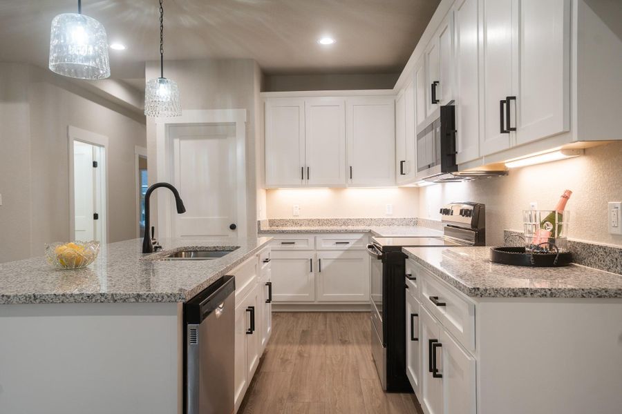 Kitchen featuring stainless steel appliances, a sink, white cabinets, an island with sink, and recessed lighting