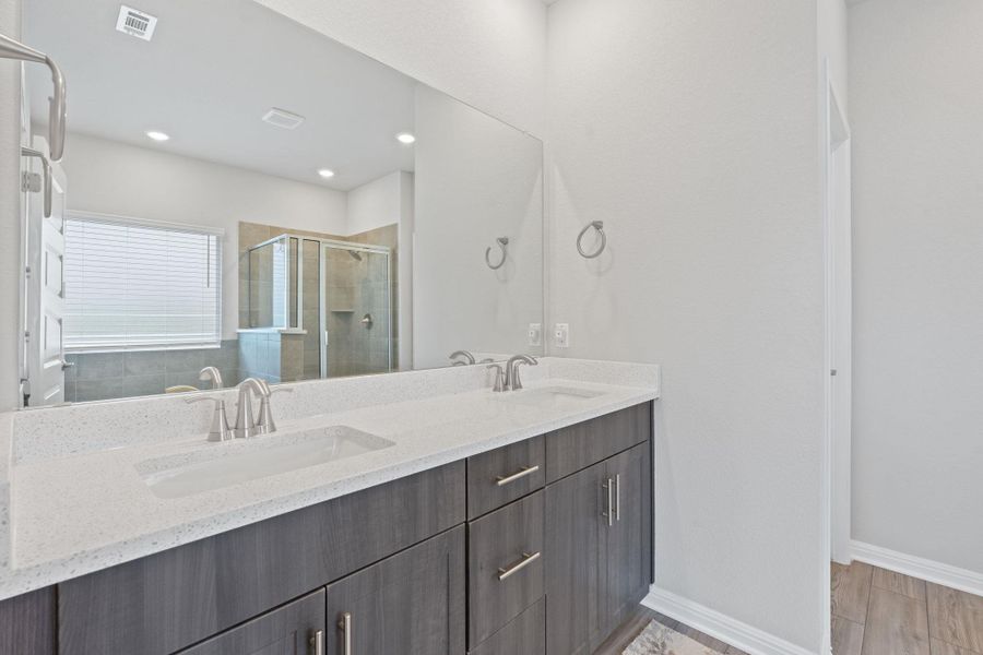 Full bath featuring double vanity, a shower stall, visible vents, and a sink Full bath featuring double vanity, a shower stall, visible vents, and a sink