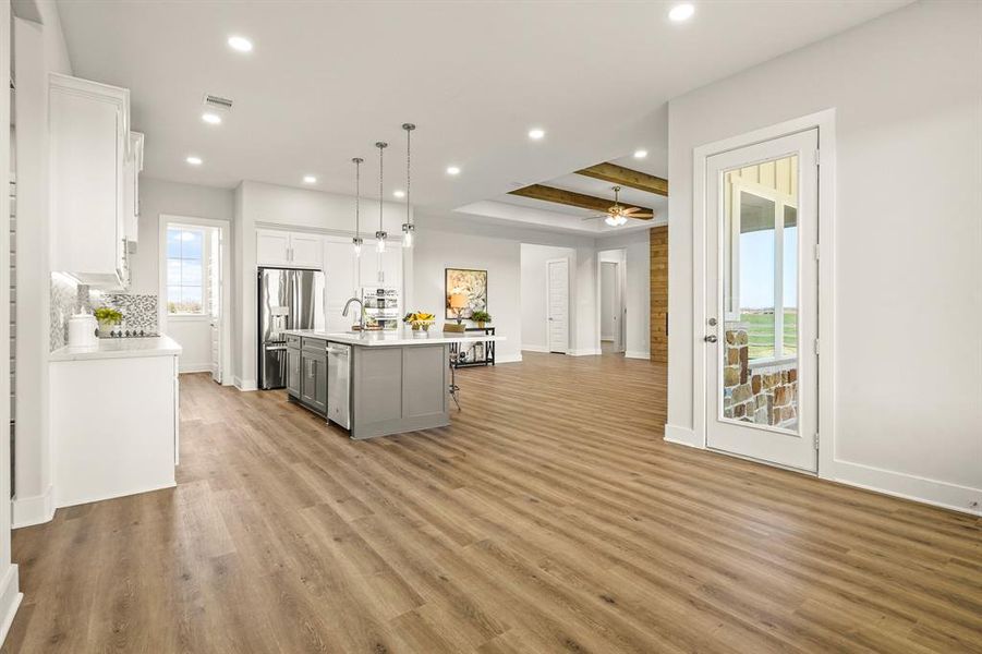 This step back showcases the highly sought after open concept design that is executed perfectly in this home. The glass-plated door ahead leads to the covered Back Patio.