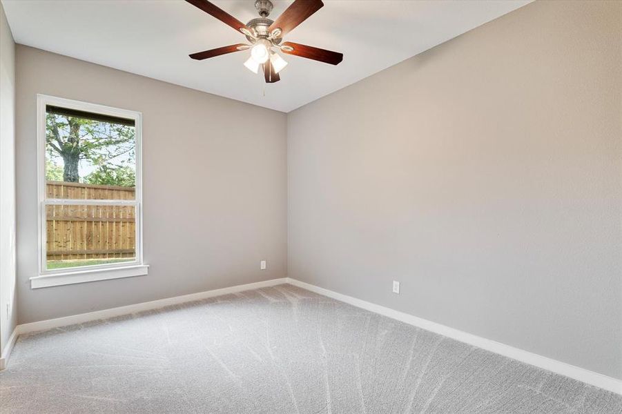 Empty room featuring ceiling fan, a wealth of natural light, and carpet Empty room featuring ceiling fan, a wealth of natural light, and carpet