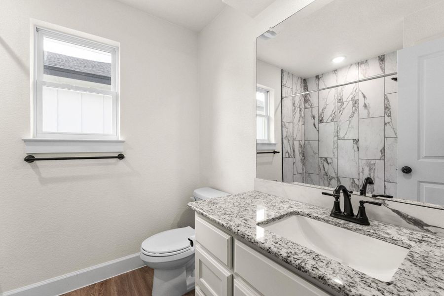 Bathroom with dark wood-style floors, vanity, and a marble finish shower