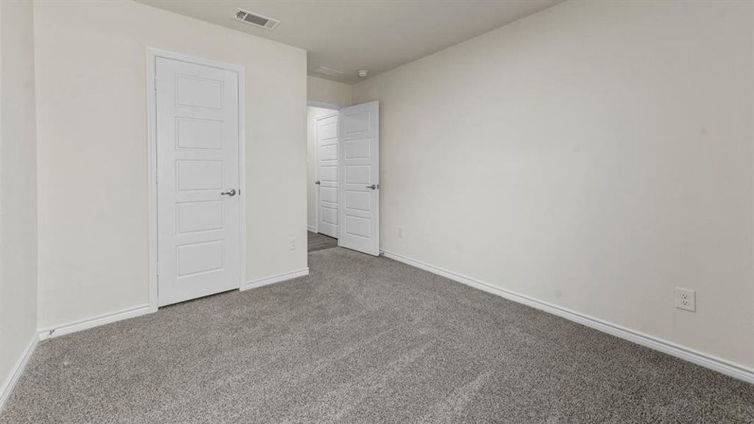 Carpeted interior space featuring light neutral wall paint, white baseboards, and white five-panel interior doors with brushed nickel hardware