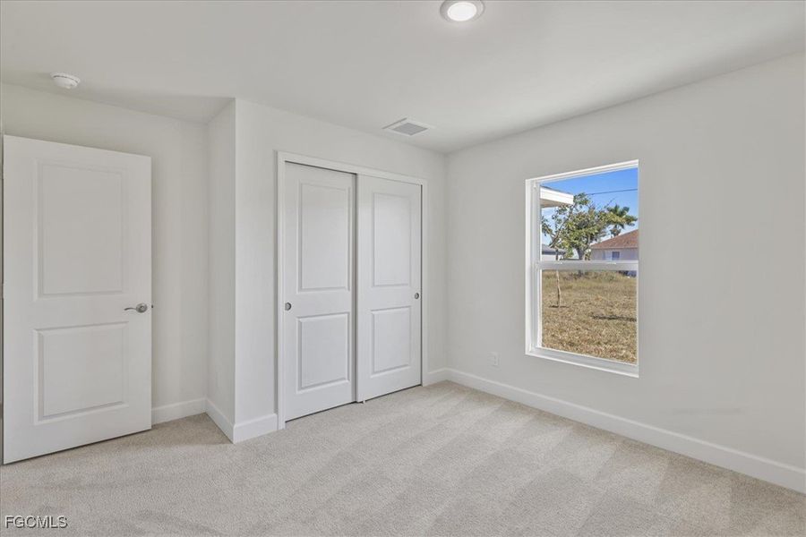 Unfurnished bedroom featuring light colored carpet and a closet