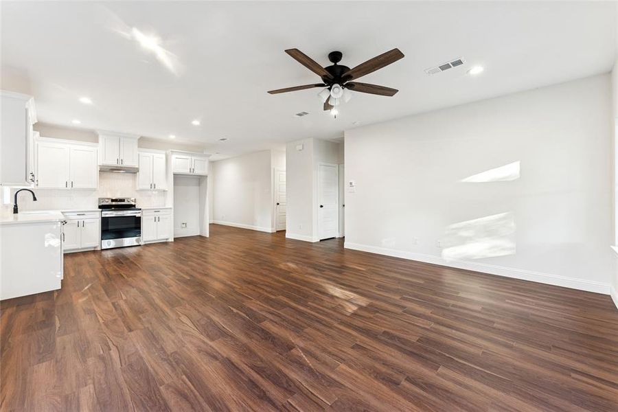 Unfurnished living room with dark wood-style flooring, ceiling fan, and recessed lighting