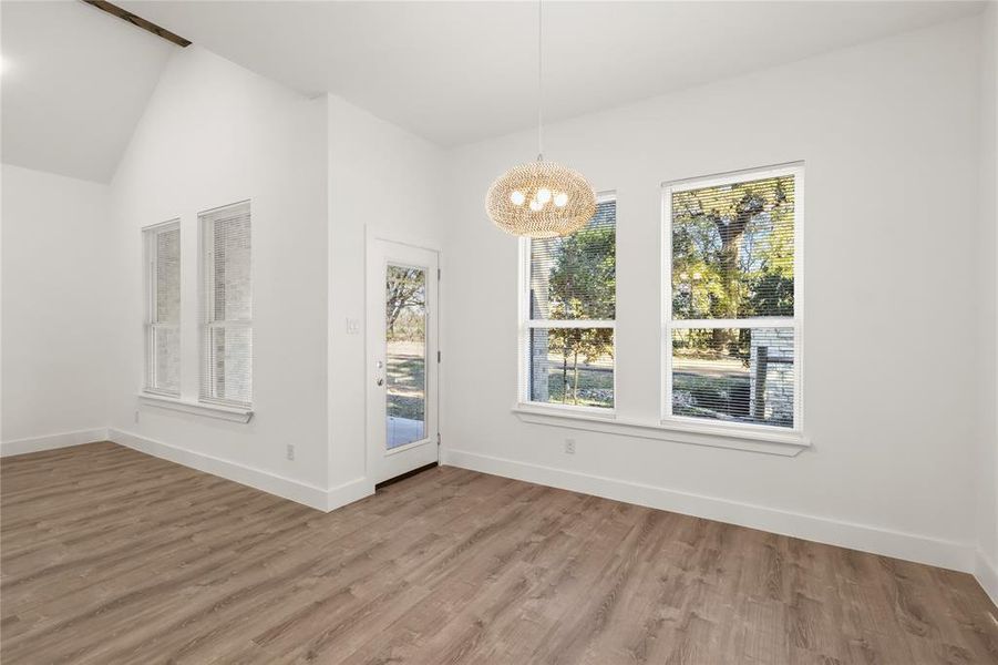 Unfurnished dining area featuring hardwood / wood-style floors, lofted ceiling, and a chandelier