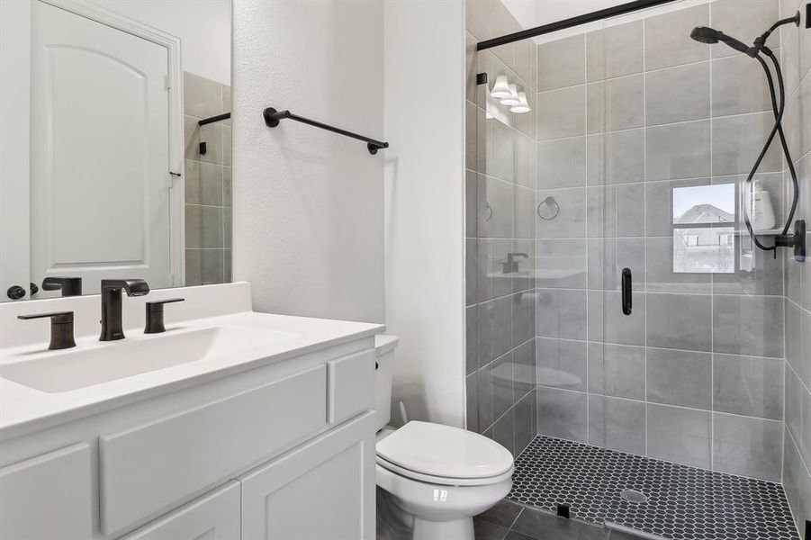 Bathroom featuring toilet, vanity, and a shower stall Bathroom featuring toilet, vanity, and a shower stall