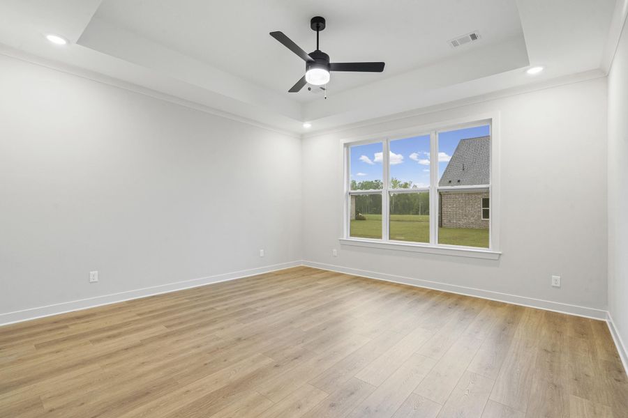 Spacious room featuring wood-finish flooring and a large window with a bright exterior Spacious room featuring wood-finish flooring and a large window with a bright exterior