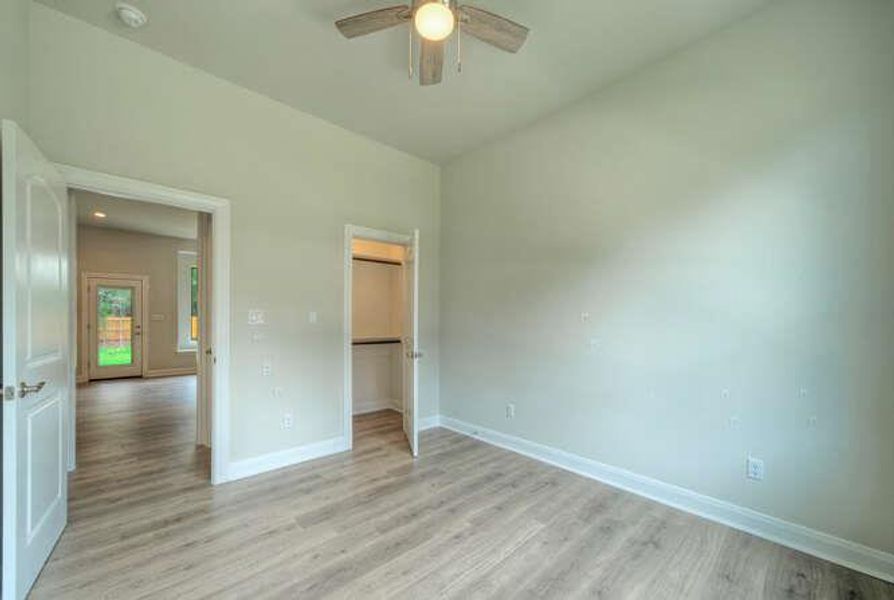 Unfurnished bedroom featuring light wood-style floors, a spacious closet, and ceiling fan