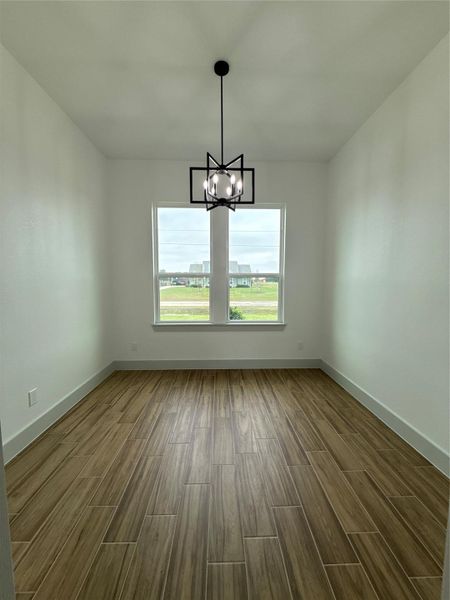 This dining room features a modern light fixture and large window providing natural light. It has wood-look tile flooring, white walls, and a clean, minimalist design and modern light fixture. This dining room features a modern light fixture and large window providing natural light. It has wood-look tile flooring, white walls, and a clean, minimalist design and modern light fixture.