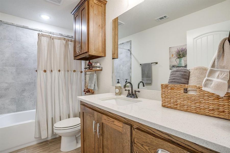 Full bathroom featuring shower/bath combo, vanity, and light wood-style tile flooring Full bathroom featuring shower/bath combo, vanity, and light wood-style tile flooring