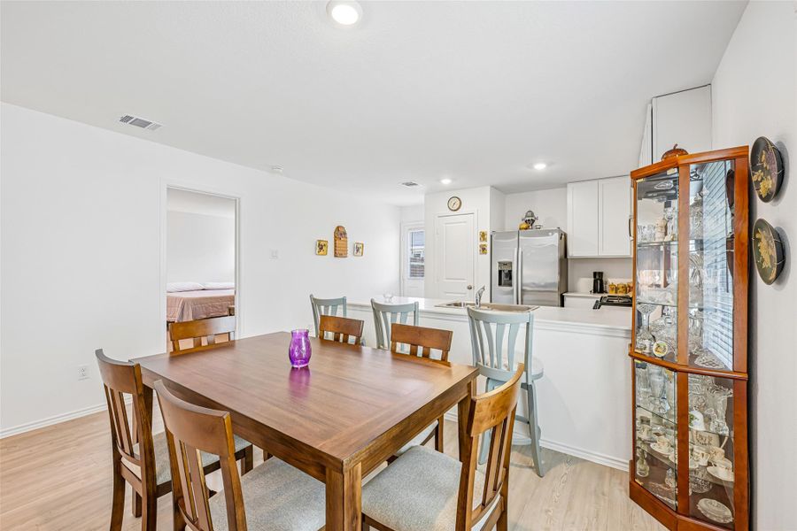 Open-concept dining area featuring wood-finish flooring, a wood dining table, and recessed ceiling lighting Open-concept dining area featuring wood-finish flooring, a wood dining table, and recessed ceiling lighting