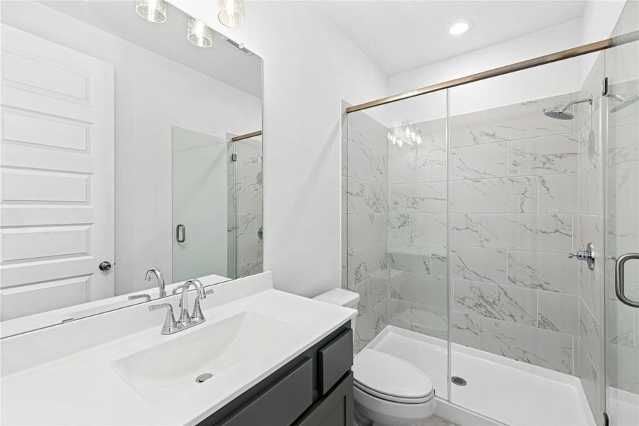 Bathroom featuring a marble finish shower and vanity