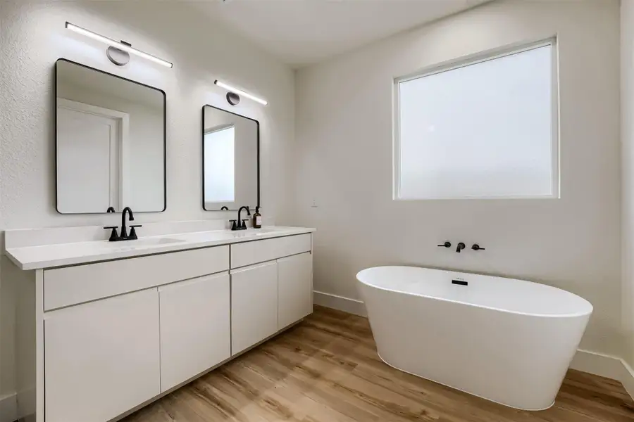 Spa-inspired primary bathroom with dual vanities, freestanding soaking tub, and designer finishes