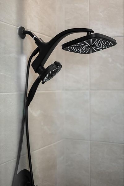 Modern matte black dual shower fixtures contrast beautifully against light stone tiled walls. Modern matte black dual shower fixtures contrast beautifully against light stone tiled walls.