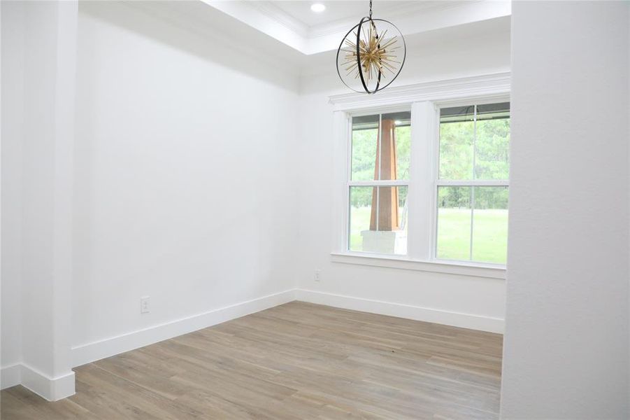 Formal dining room has a view of the front yard, sunk in ceiling, canned lighting and a custom chandelier.