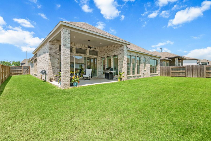 This photo showcases the spacious backyard on a corner lot with a well-maintained lawn and a covered patio. Plenty of space for a game of catch and possibly a vegetable garden on the side yard.