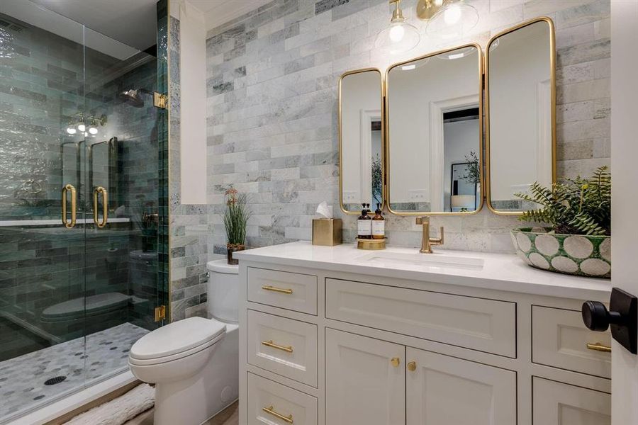 Bathroom with vanity, decorative backsplash, toilet, walk in shower, and tile walls