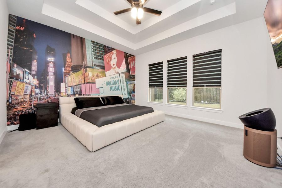 Spacious primary bedroom with tray ceilings, large windows, and abundant natural light.