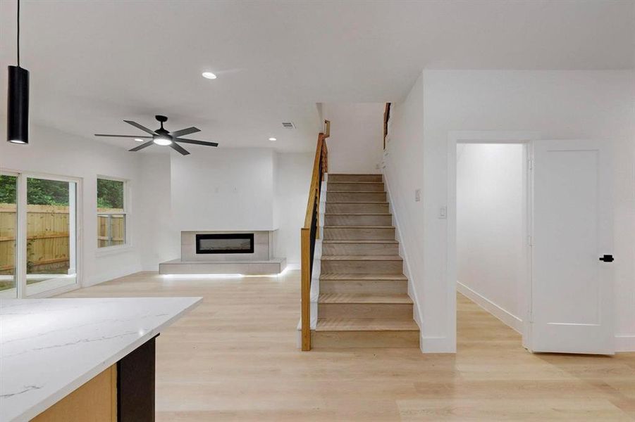 Stairway with a fireplace with raised hearth, recessed lighting, wood finished floors, and ceiling fan Stairway with a fireplace with raised hearth, recessed lighting, wood finished floors, and ceiling fan