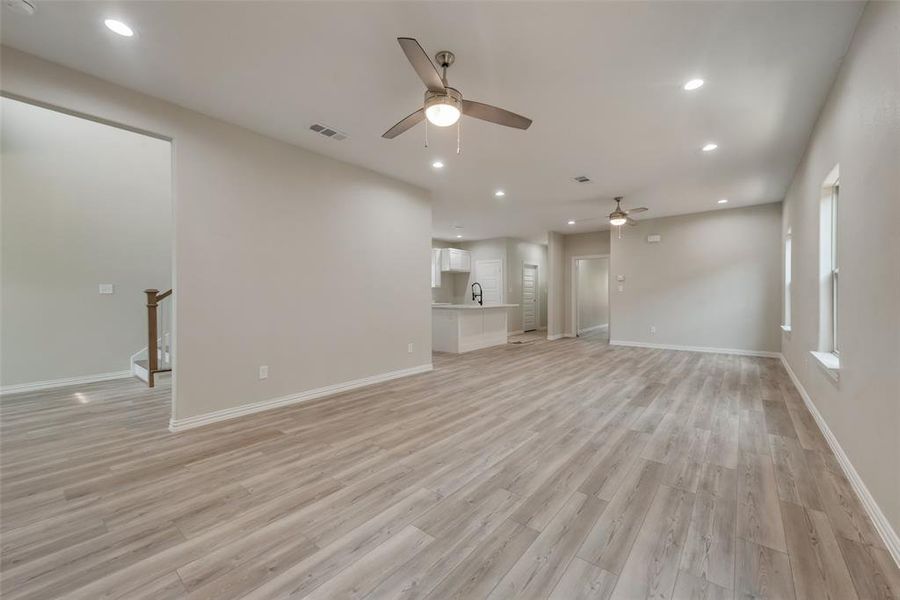 Unfurnished living room with sink, ceiling fan, and light wood-type flooring