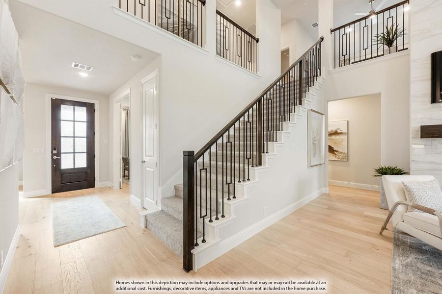 Two-story foyer with carpeted staircase, iron balusters, hardwood floors, and dark wood front door with glass panels