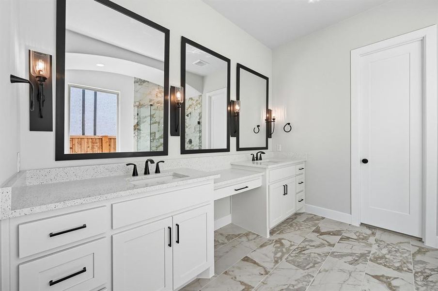 Bathroom with a marble finish shower, light marble finish flooring, and two vanities