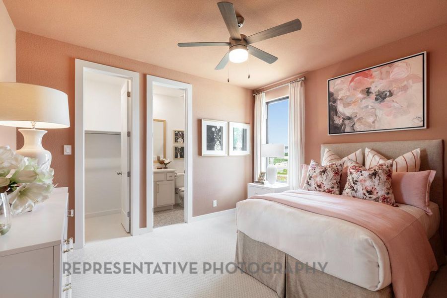 Bedroom with light colored carpet, connected bathroom, and a ceiling fan
