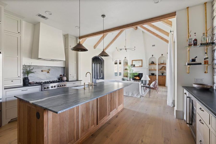 Kitchen featuring beam ceiling, light hardwood / wood-style floors, sink, and custom exhaust hood