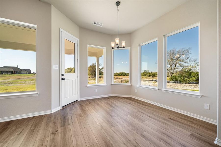 Unfurnished dining area featuring a chandelier, light wood-style floors, and plenty of natural light