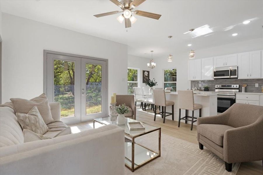 Living room featuring french doors, ceiling fan with notable chandelier, and light hardwood / wood-style flooring