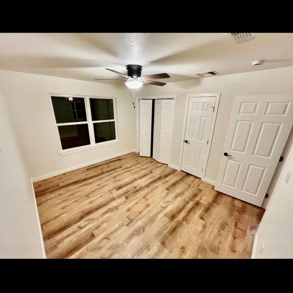 A quiet bedroom showcases durable wood flooring and ample natural light through a generous window.