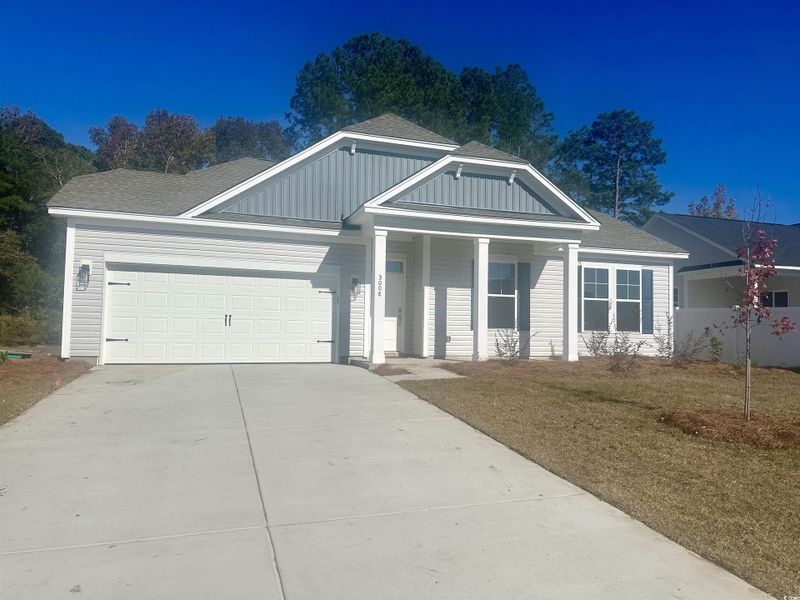 View of front of home with a shingled roof, concrete driveway, an attached garage, a front lawn, and covered porch