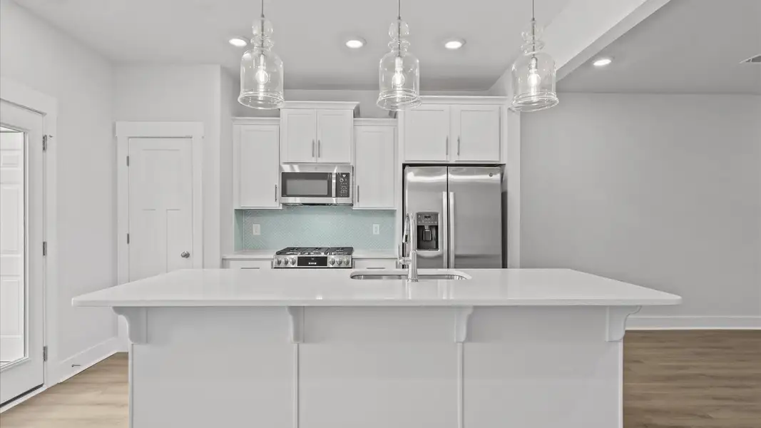 Tasteful design meets functional luxury in this kitchen with a 9-foot island and modern pendant lighting