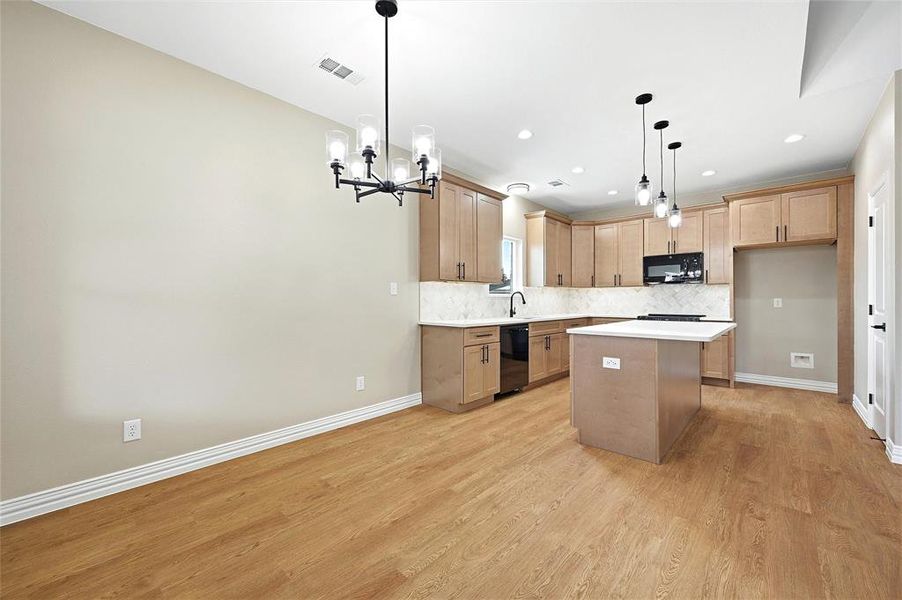 Kitchen with a center island, tasteful backsplash, light wood-type flooring, and suspended lighting Kitchen with a center island, tasteful backsplash, light wood-type flooring, and suspended lighting