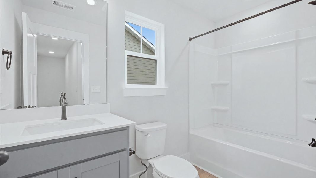 First-rate full bath featuring modern surfaces and a fresh, current color palette by DRB Homes