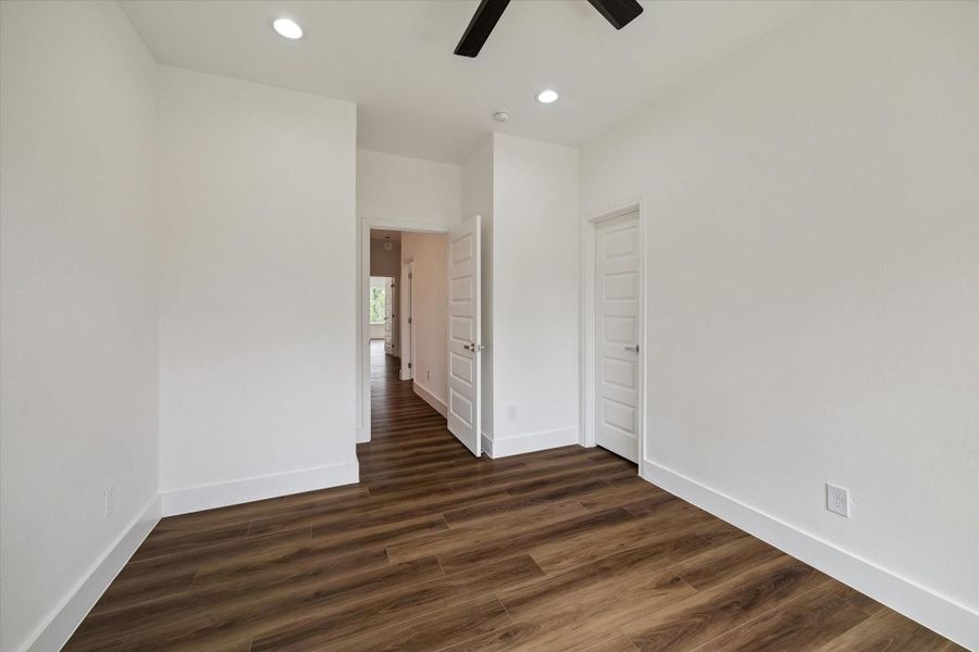 Spacious and serene, this bedroom features warm wood-look flooring, crisp white walls, recessed lighting, and a modern ceiling fan. The clean-lined design creates a fresh, contemporary atmosphere, while multiple doors provide convenient access to adjoining spaces and storage. Generous wall space allows plenty of flexibility for furniture placement, making the room easy to personalize as a comfortable bedroom, guest suite, or private retreat. Spacious and serene, this bedroom features warm wood-look flooring, crisp white walls, recessed lighting, and a modern ceiling fan. The clean-lined design creates a fresh, contemporary atmosphere, while multiple doors provide convenient access to adjoining spaces and storage. Generous wall space allows plenty of flexibility for furniture placement, making the room easy to personalize as a comfortable bedroom, guest suite, or private retreat.