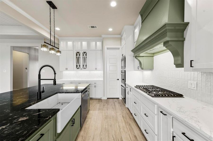 Kitchen featuring appliances with stainless steel finishes, sink, decorative light fixtures, white cabinets, and light hardwood / wood-style floors